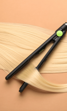 A flat iron hair straightener gliding over blonde hair.