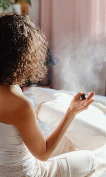 A woman using a hair spray or mist on her curly hair.